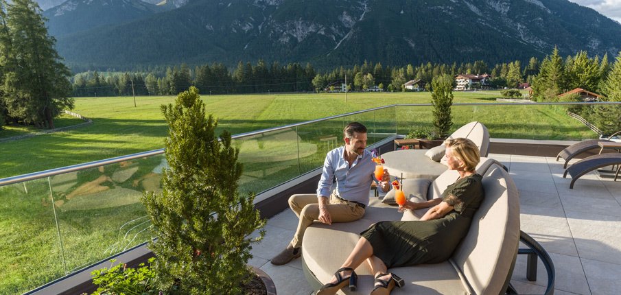 Foto: Paar auf der Dachterrasse vom Adults only Spa Hotel Leutasch in Österreich Tirol im Last Minute Urlaub mit Hund.